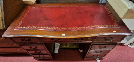 A contemporary mahogany and gilt tooled rouge leather inset twin pedestal writing desk, having a