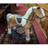 A contemporary plush fabric upholstered standing horse, with tan leather saddle, length 95cm