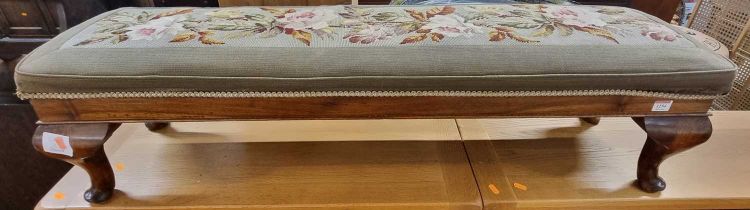 A walnut and floral tapestry embroidered long footstool, on squat cabriole supports, length 120.5cm