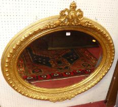 *A large contemporary profusely floral gilt decorated bevelled oval wall mirror, having pierced