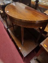 An early 19th century mahogany and crossbanded D-shaped baize lined fold-over card table, having