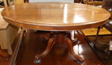 A mid-Victorian mahogany oval tilt-top pedestal loo table, raised on hipped scroll supports,