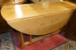 A contemporary blond oak dropleaf dining table, having opposing double gateleg action, raised on