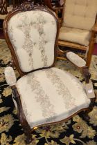 A Victorian carved rosewood framed nursing chair, having cream needlework floral button back