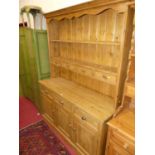 A rustic stained pine kitchen dresser, having two-tier open plate rack, four short drawers over base