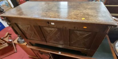 An 18th century joined oak three-panelled hinge top coffer, the later relief carved front panels