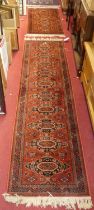 Two Persian style red ground woollen Bokhara hall runners, the longer 270 x 69cm, the shorter 135