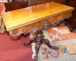 An early Victorian mahogany fold-over card table, having a floral carved apron to conforming