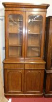 A mid Victorian mahogany round cornered bookcase cupboard, having twin arched glazed upper doors
