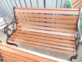 A black painted pierced and cast iron ended and stained slatted wood two-seater garden bench,