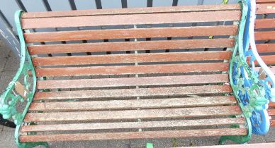 A green painted pierced and cast iron ended and stained slatted wood two-seater garden bench,