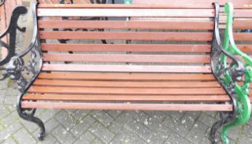 A black painted pierced and cast iron ended and stained slatted wood two-seater garden bench,