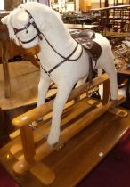 A plush upholstered child's rocking horse, having a tan leather saddle and raised on beech stand