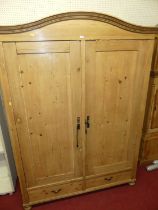 A French pine double door armoire having arched top, recessed panelled doors over twin short lower
