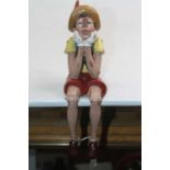 A composite figure of Pinocchio, modelled seated, h.27cm