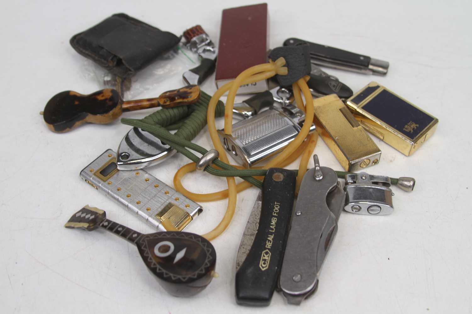 A collection of miscellaneous items to include lighters, pocket knives, and a slingshot