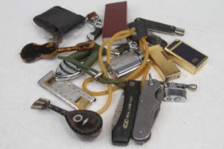 A collection of miscellaneous items to include lighters, pocket knives, and a slingshot