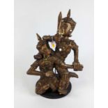 A Tibetan carved hardwood gilt painted and glass embellished figure group of two warriors, on