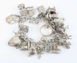 A silver charm bracelet containing numerous silver and white metal charms, single ring etc, with