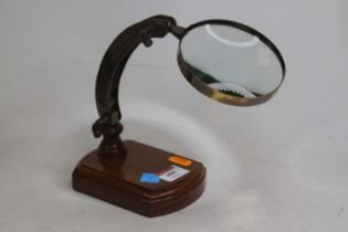 A reproduction table magnifying glass, mounted to a wooden base, h.24cm (extended)