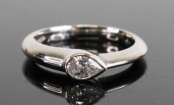 A platinum diamond solitaire ring, comprising a pear cut diamond in a bezel setting, diamond