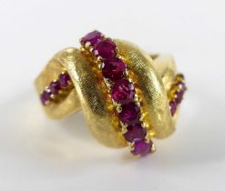 A yellow metal ruby multi-stone scrollwork ring, featuring a centre band of eight round cut rubies