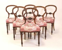 A set of six mid-Victorian walnut balloon back salon chairs, each with carved centre rails, silk
