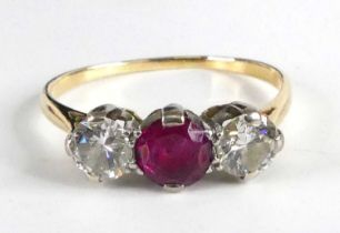 A yellow and white metal, ruby and diamond three-stone ring, featuring a centre round faceted ruby