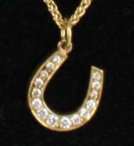 An 18ct yellow gold diamond set horseshoe pendant, having 15 graduated round brilliant cut