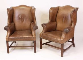 A pair of tan leather upholstered wing armchairs, in the Georgian style, 20th century, each with