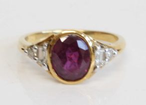 An 18ct yellow gold ruby and diamond dress ring comprising an oval ruby in a bezel setting with a