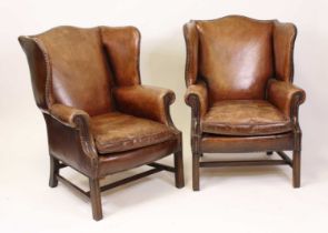 A pair of tan leather wing armchairs in the Georgian style, 20th century, each having brass