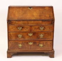 An early 18th century walnut writing bureau having a cross banded sloping fall, opening to reveal an