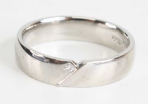 A platinum 4.35mm crossover style court shaped wedding band, having a 1.6mm Princess cut diamond