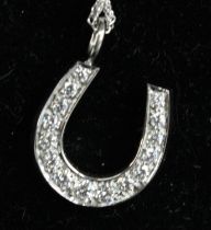 A white metal diamond set horseshoe pendant, having 15 graduated round brilliant cut diamonds in