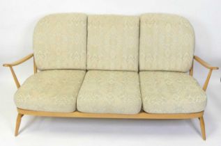 An Ercol blond beech stickback three-seater Windsor sofa, having slightly pronounced arm rests,