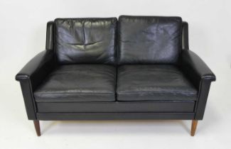 A 1960s Danish black leather two-seater sofa, having squab cushion backs and seats, raised on turned