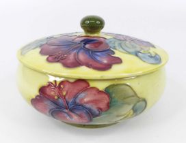 An early 20th century Moorcroft Hibiscus pattern pottery footed dressing table tidy and cover, of