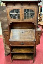 In the manner of Liberty & Co - an Arts & Crafts oak bureau/bookcase, having twin lead glazed