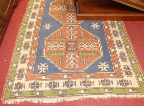 A Turkish woollen red ground rug, having twin stylised octagonal floral decorated panels within