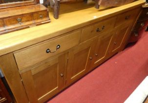 A contemporary blond oak long sideboard, having three frieze drawers over four lower panelled
