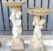 Two similar reconstituted stone bird baths, each supported by semi-nude cherub figures, the larger