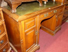 A late Victorian walnut kneehole writing desk, having a gilt tooled green leather inset surface over