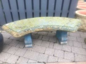 A blue painted reconstituted stone curved garden bench, raised on scroll end pedestal supports,