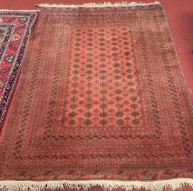 A Persian woollen red ground Bokhara rug, 300 x 232cm