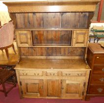 A joined oak Welsh dresser, having two-tier open plate rack with twin small cupboard compartments,