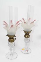 A pair of 20th century oil lamps, each having cranberry tipped frosted glass shade with frilled rim,