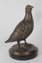 A bronzed metal model of a partridge, shown standing on naturalistic base and mounted to a