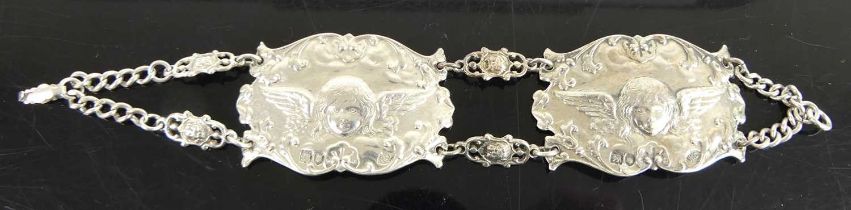A circa 1900 silver bracelet, arranged as two panels chased with winged cherubs, 35.5g Age related