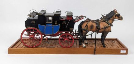 A painted wooden model of a stagecoach with two matt-glazed pottery horses, mounted to a wooden